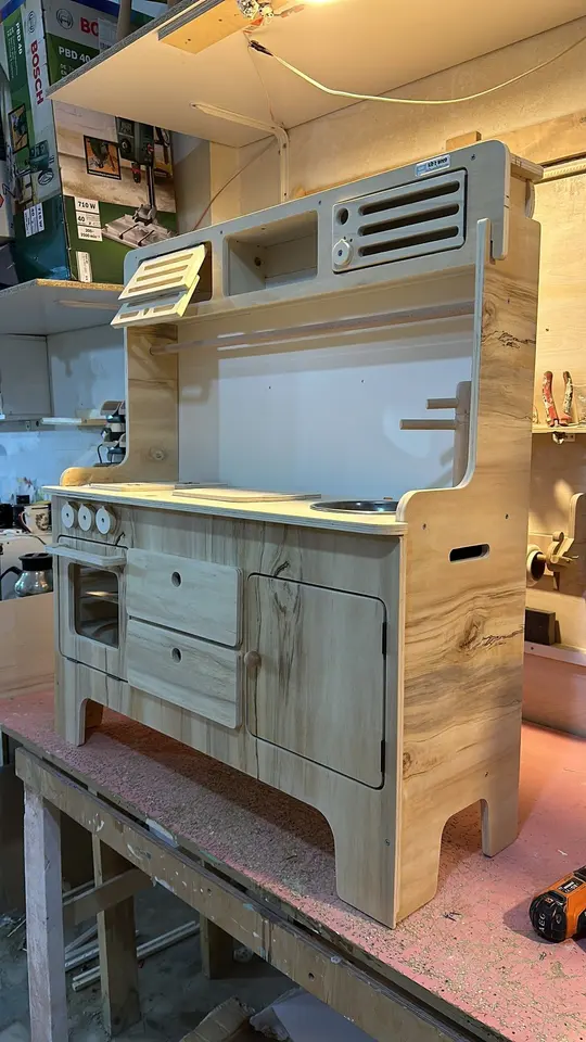 Handcrafted wooden toy play kitchen on a workshop workbench